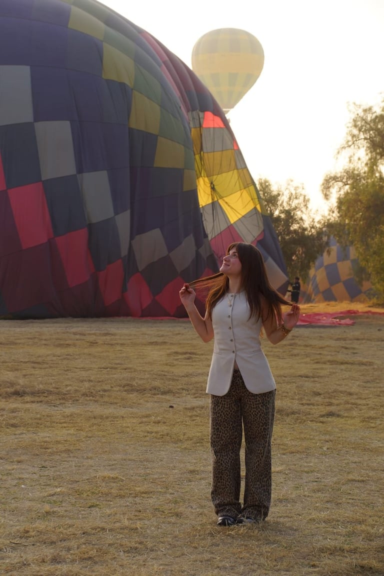 Woman standing in front of colorful hot air balloons on the ground during dawn or sunrise