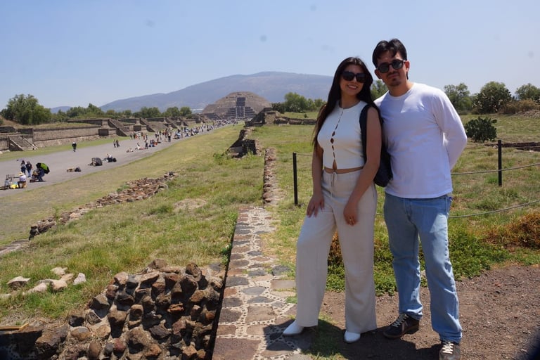 Couple posing at Teotihuacan archaeological site in Mexico with pyramid mountain and ancient ruins visible in background